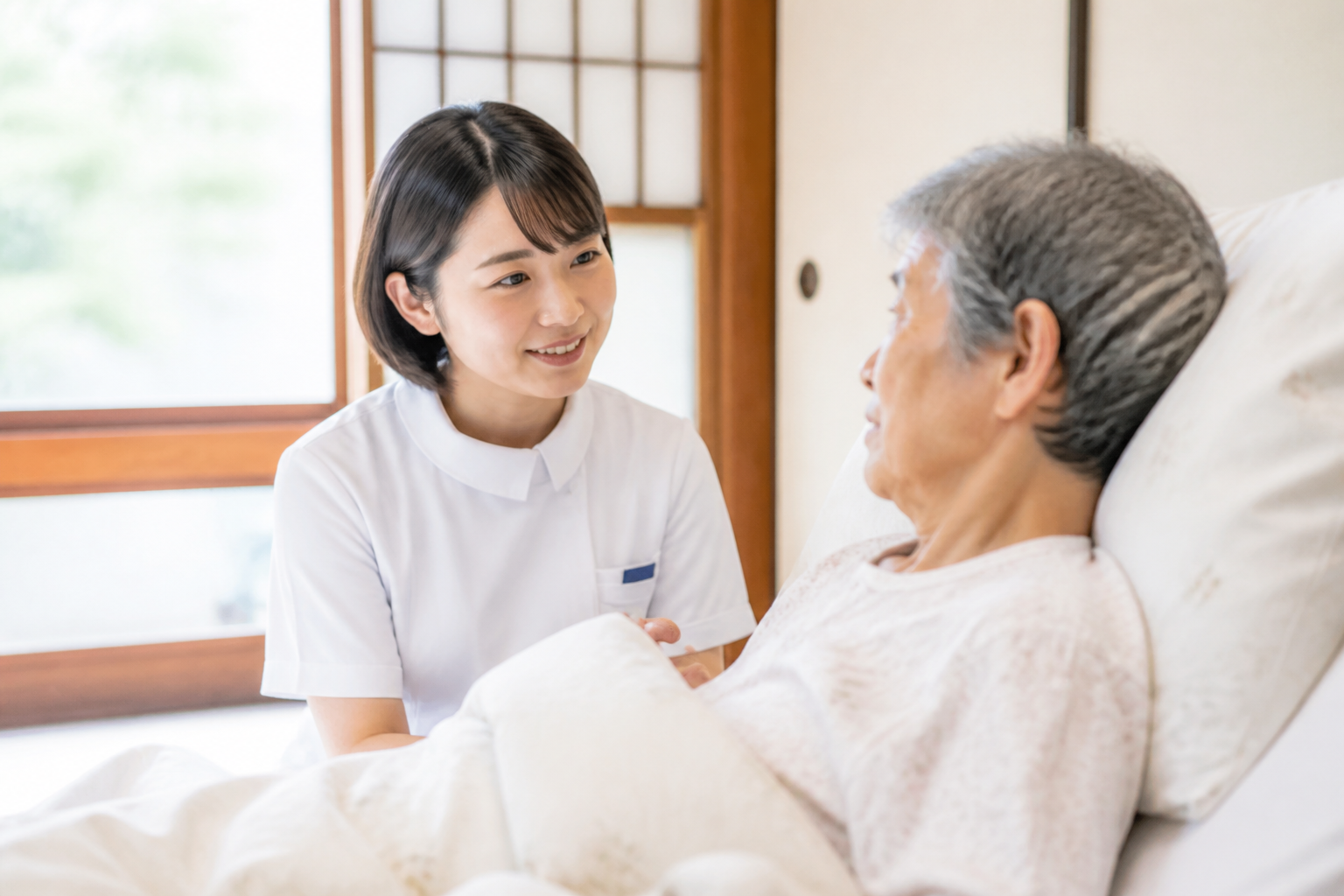 訪問看護師がが在宅療養中のがん末期患者のベッドサイドで寄り添っている様子