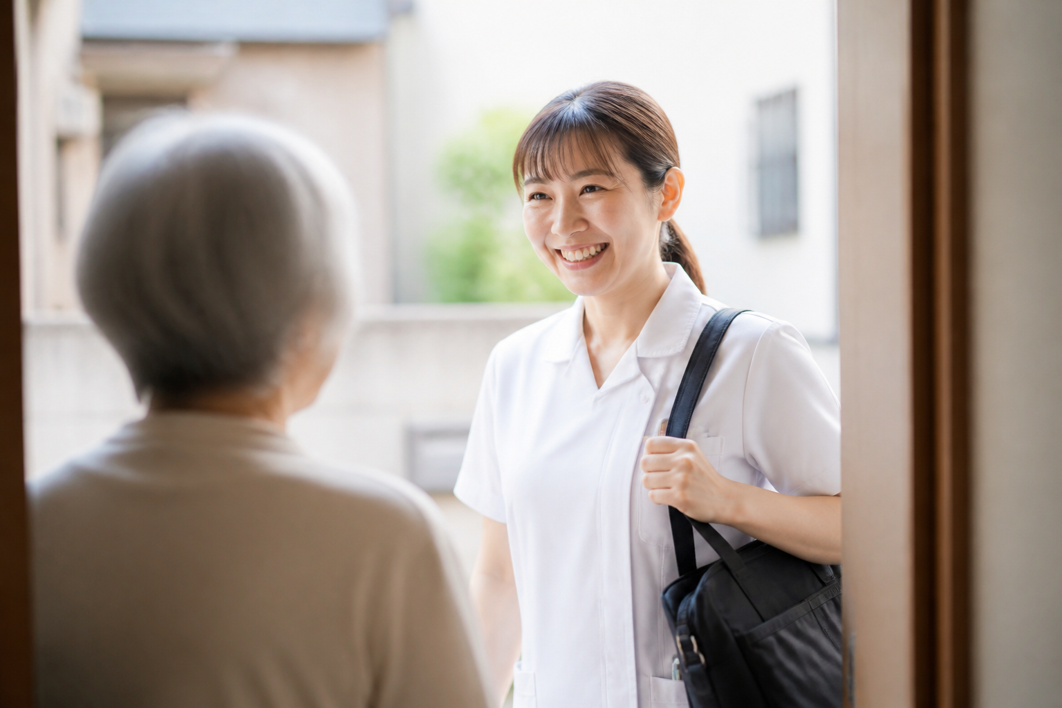 訪問看護師が利用者宅の玄関先で笑顔で挨拶している場面