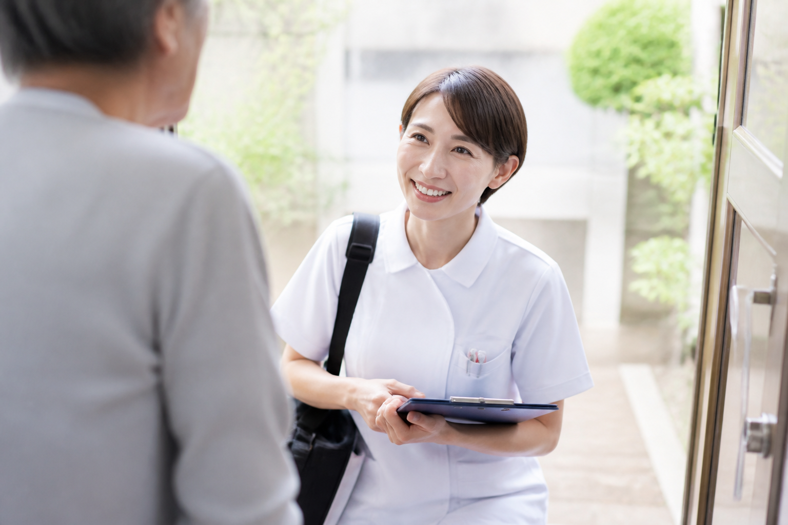 訪問看護師が患者宅の玄関先で対応している場面