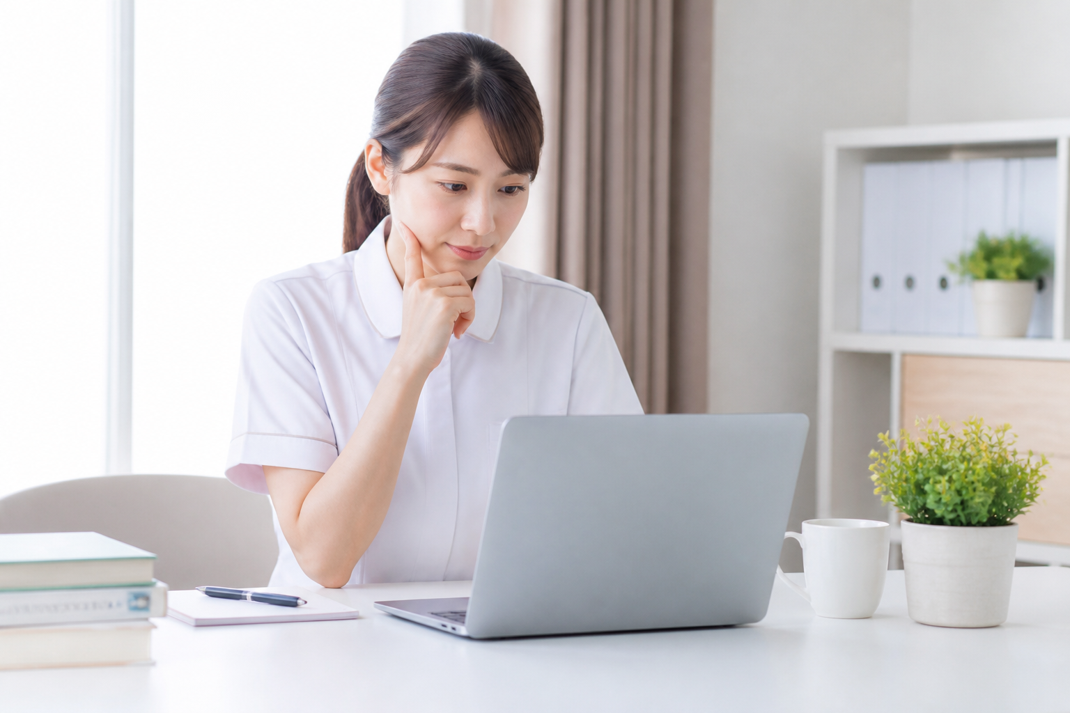 訪問看護への転職を検討しノートパソコンで情報収集する日本人女性看護師